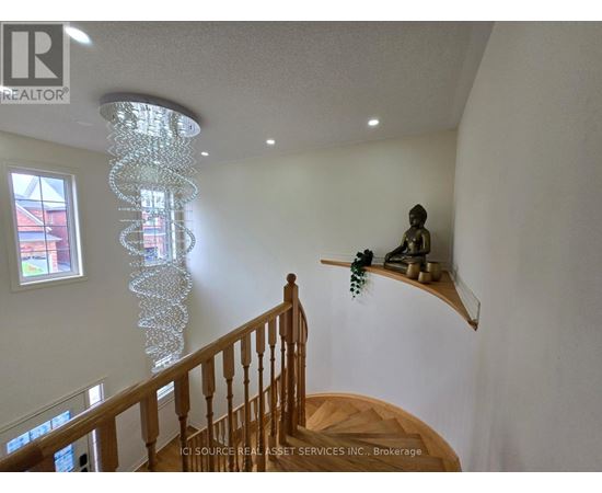 A chandelier hangs from the ceiling in a room with a wooden staircase.