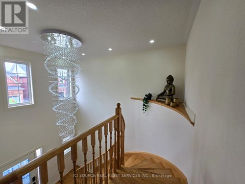 A chandelier hangs from the ceiling in a room with a wooden staircase.