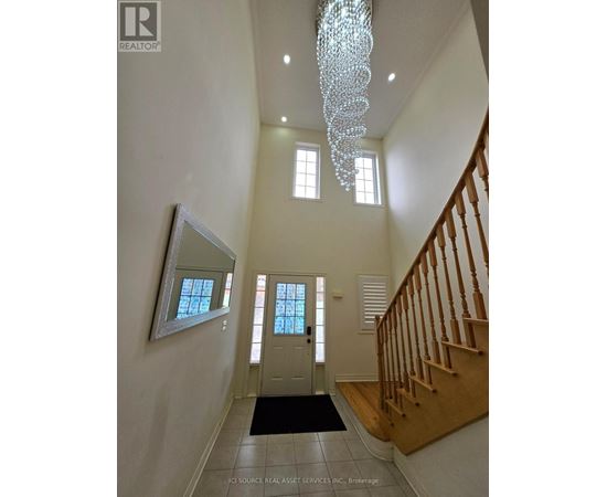 A hallway with a chandelier, a mirror, and a staircase.