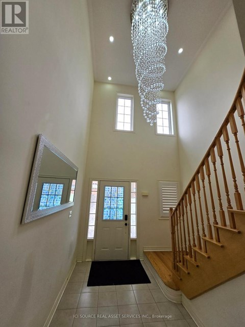 A hallway with a chandelier, a mirror, and a staircase.