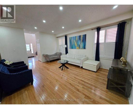 A living room with a white couch and a blue ottoman.