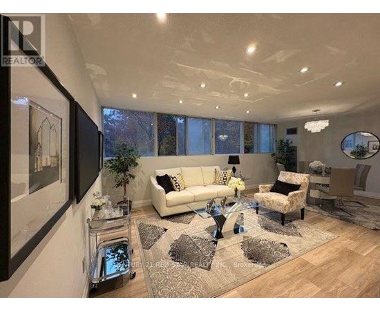 A well-lit living room with a white sofa and a glass coffee table.