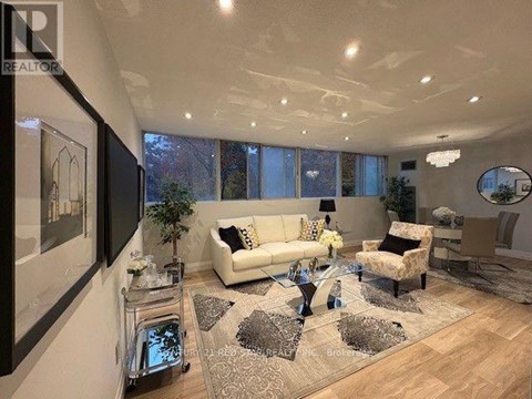 A well-lit living room with a white sofa and a glass coffee table.
