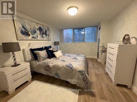 A bedroom with a bed, nightstand, and a painting on the wall.