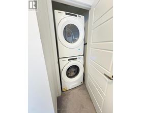 A white Whirlpool dryer is on top of a white Whirlpool washer in a small laundry room.