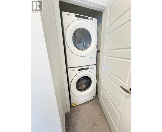 A white Whirlpool dryer is on top of a white Whirlpool washer in a small laundry room.