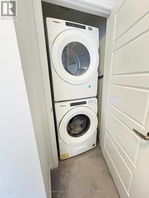 A white Whirlpool dryer is on top of a white Whirlpool washer in a small laundry room.