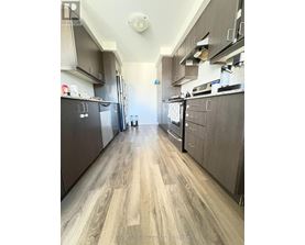A kitchen with wood flooring and dark cabinets.