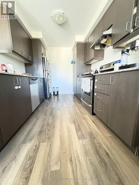 A kitchen with wood flooring and dark cabinets.