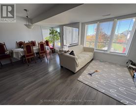 A living room with a couch, chairs, and a dining table.