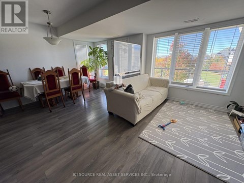 A living room with a couch, chairs, and a dining table.
