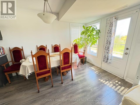 A dining room with a table set for six with chairs with red covers.