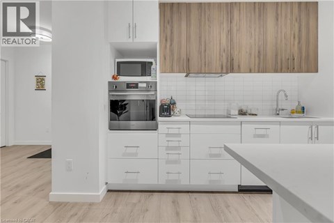 A modern kitchen with white cabinets and a wooden backsplash.