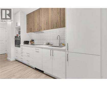 A modern kitchen with white cabinets and a wooden overhead.