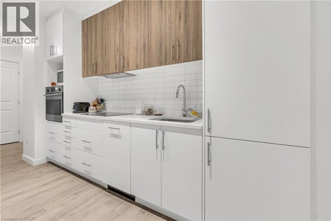 A modern kitchen with white cabinets and a wooden overhead.