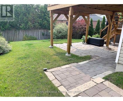 A backyard with a wooden pergola and a stone walkway.