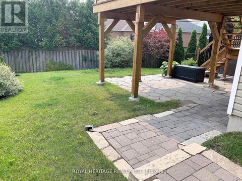 A backyard with a wooden pergola and a stone walkway.