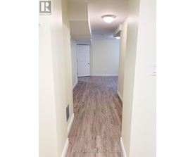 A hallway with wood flooring and white walls.