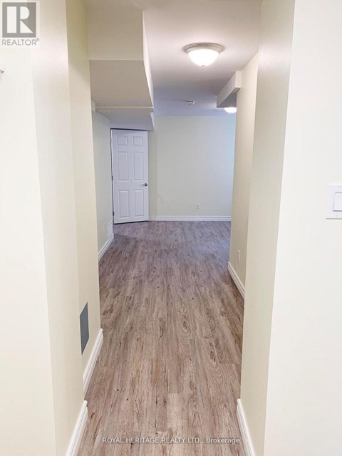 A hallway with wood flooring and white walls.