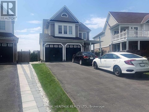 A white car is parked in front of a house with a garage.