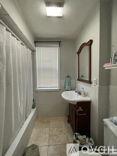 A bathroom with a sink, mirror, and bathtub.