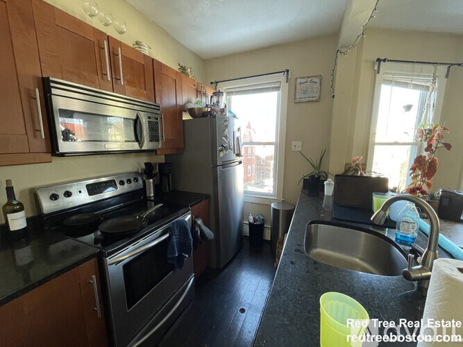 A kitchen with a black counter top and stainless steel appliances.