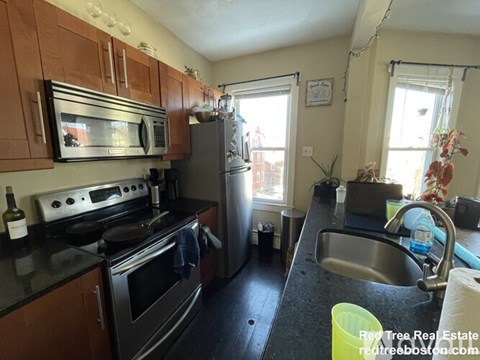 A kitchen with a black counter top and stainless steel appliances.