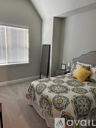 A bedroom with a patterned bedspread and a bed with a yellow pillow.