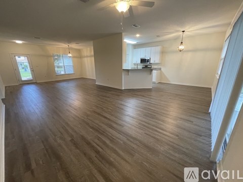 A spacious room with wooden flooring and a ceiling fan.