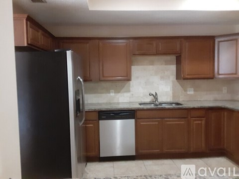A kitchen with brown cabinets and a black refrigerator.