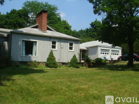 A house with a chimney is surrounded by trees and grass.