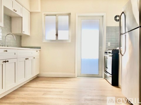 A kitchen with white cabinets and a black fridge.