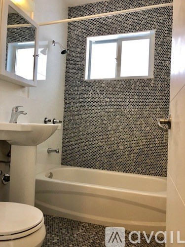 A bathroom with a white toilet, a sink, a bathtub, and a window.