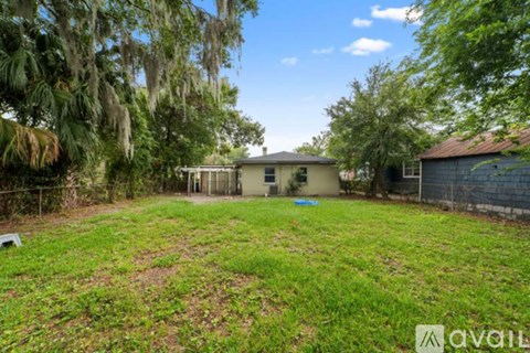 A backyard with a fence and a tree with Spanish moss hanging from it.