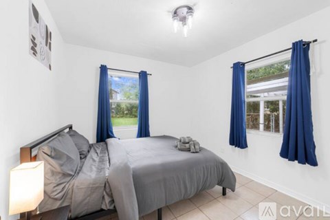 A bedroom with two beds and blue curtains.