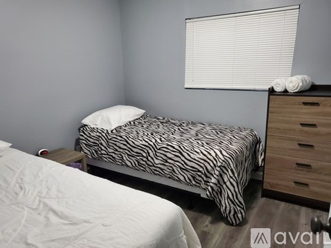 A bedroom with a zebra print bed and a white bed in the background.