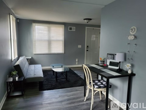 A living room with a grey couch, a black and white table, and a black rug.