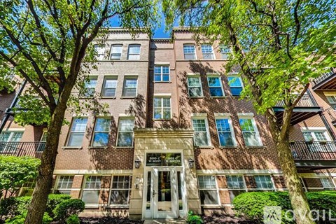 A building with a white door and windows surrounded by trees.