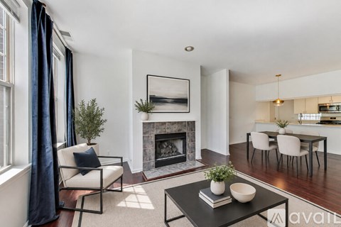 A living room with a fireplace, a chair, a table, and a painting on the wall.