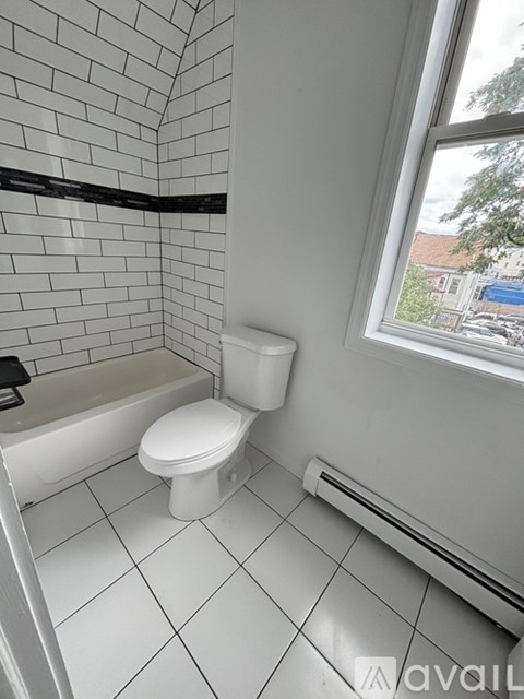 A white toilet in a small bathroom with a tiled wall.