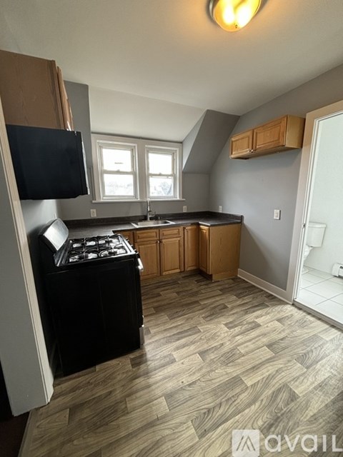 A kitchen with a black stove top oven and wooden cabinets.