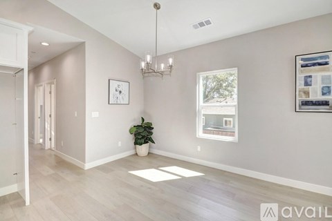 A spacious room with a chandelier, a potted plant, and a framed picture on the wall.