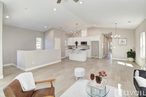 A spacious living room with a brown leather chair and a glass coffee table.