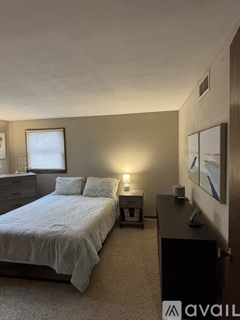 A bedroom with a bed, nightstand, and a window.
