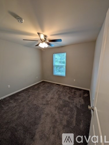 A room with a ceiling fan and a window with a view of a building.