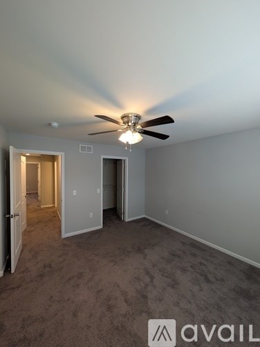A room with a ceiling fan and carpeted floor.