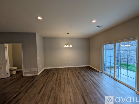 A spacious room with wooden flooring and a large window.