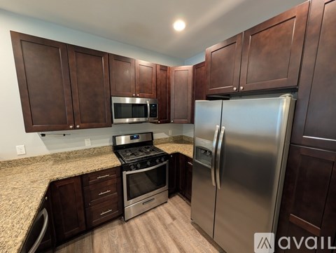 A kitchen with dark wood cabinets and stainless steel appliances.