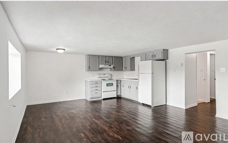 A kitchen with white appliances and wooden floors.