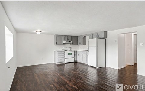 A kitchen with white appliances and wooden floors.